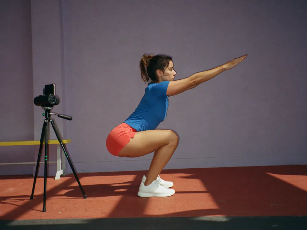 Athlete squatting in front of a phone on a tripod